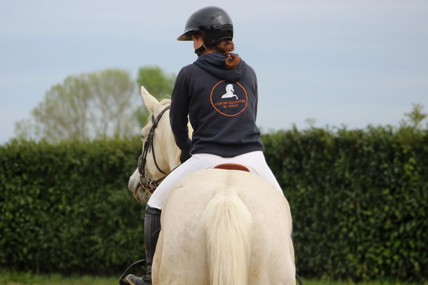 Cavalière du Centre Équestre de Venat montant un cheval blanc en carrière